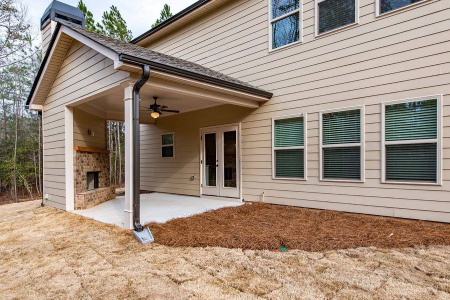 Stone and wood cottage with a green lawn, blue sky, and trees.