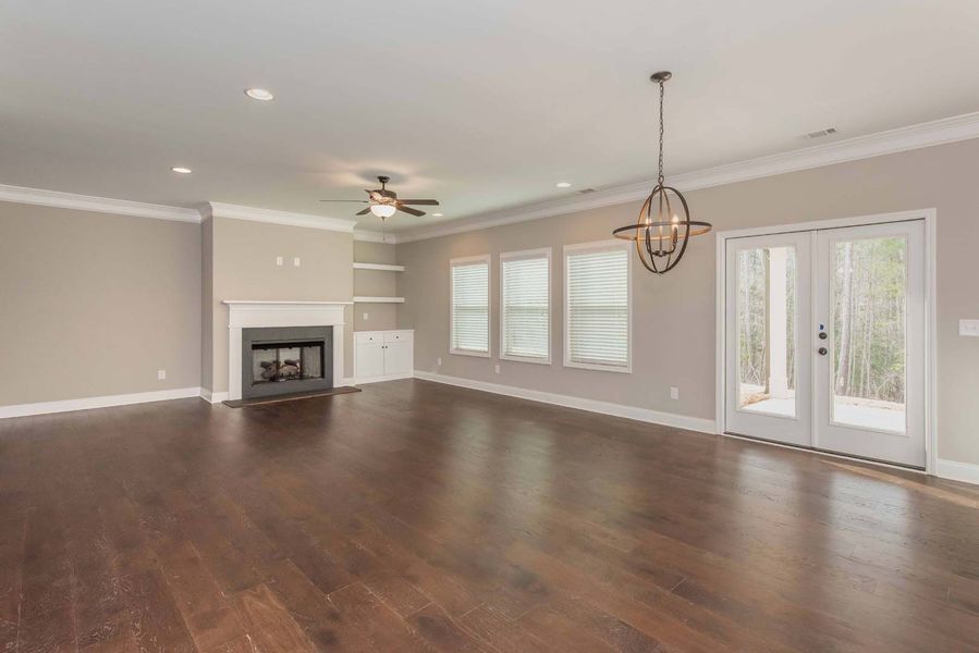 Empty living room with hardwood floors, fireplace, and a chandelier.