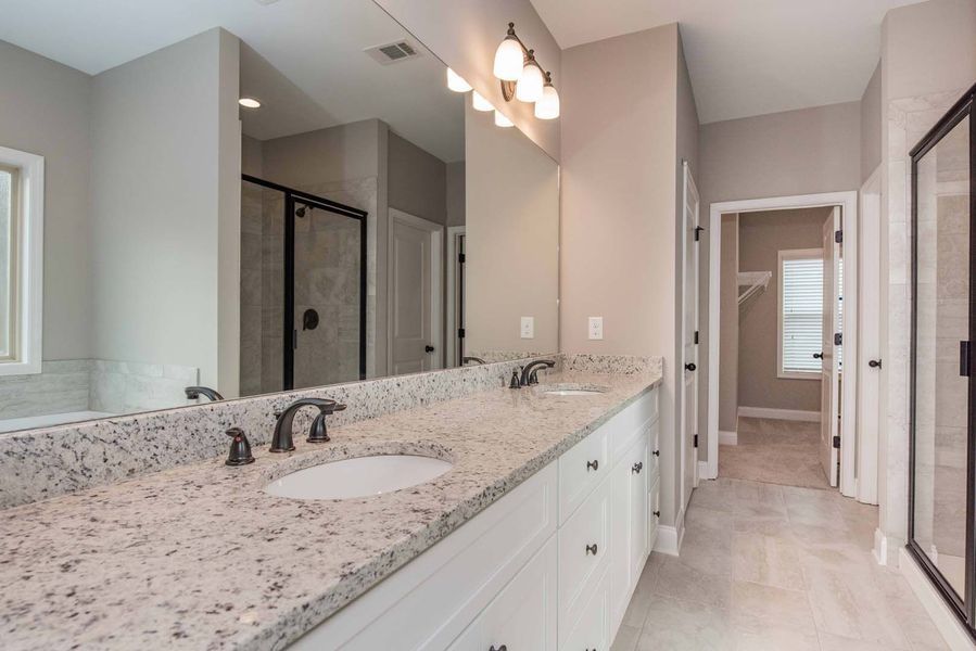 Bathroom with white cabinets, granite countertop, large mirror, and walk-in closet.