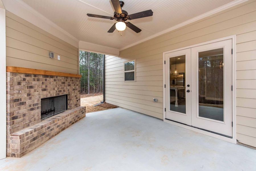 Covered patio with brick fireplace, French doors, and ceiling fan.