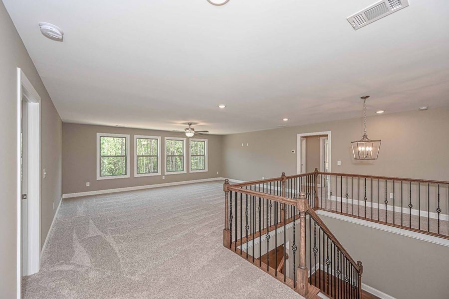 Loft area with stairs, windows, gray walls, carpet, and chandelier.