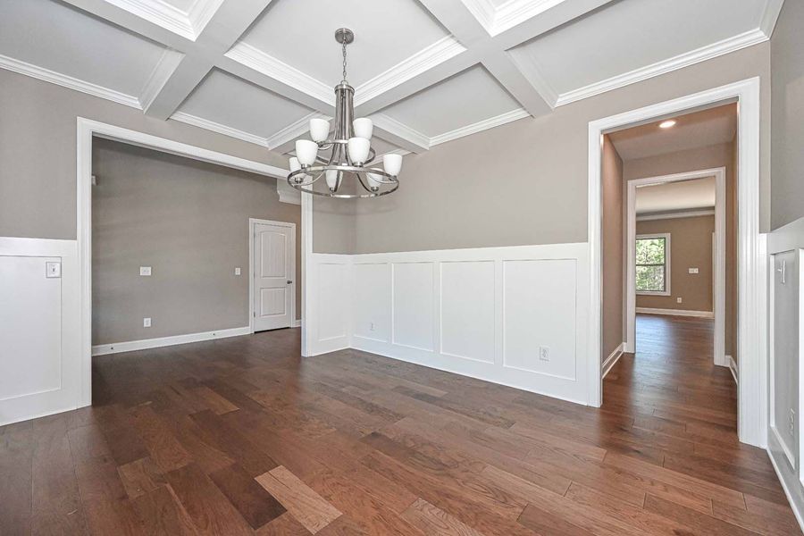 Dining room with dark wood floor, wainscoting, gray walls, white ceiling, and chandelier.