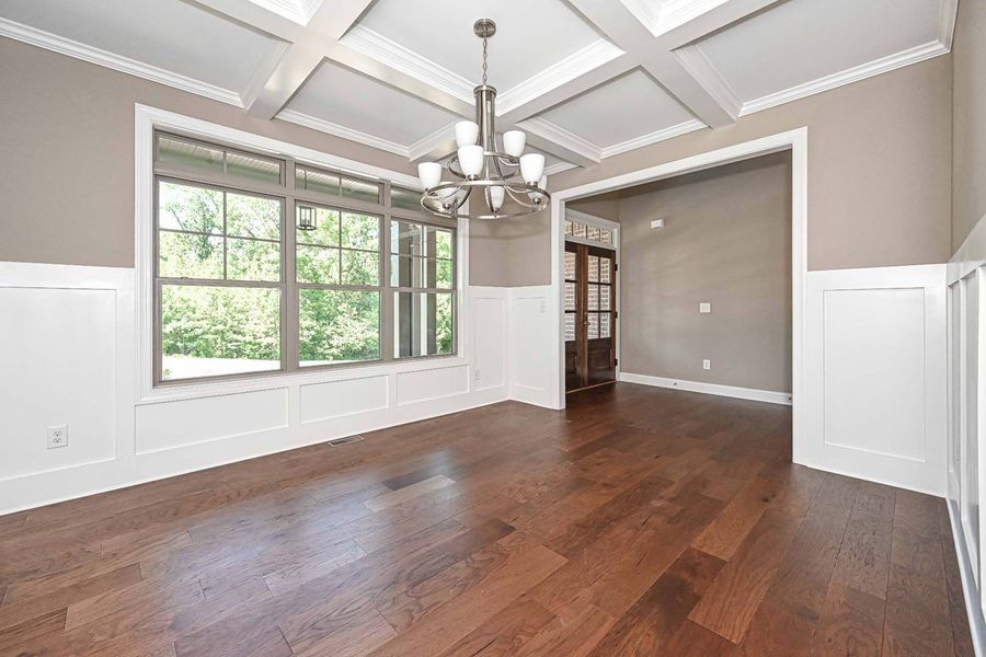 Empty dining room with hardwood floors, large window, and decorative ceiling.