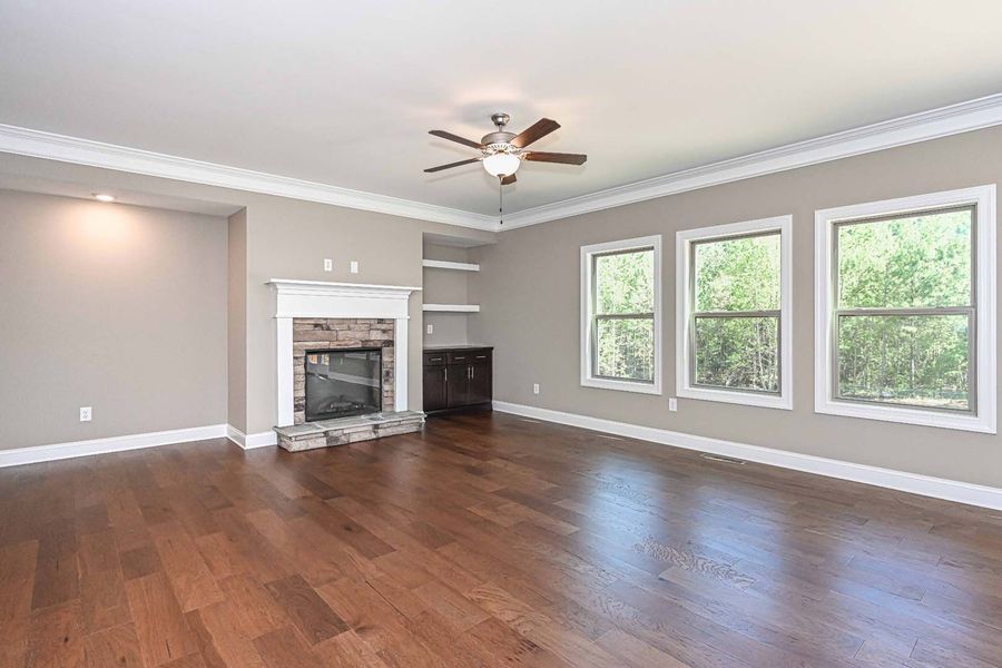Living room with fireplace, built-ins, three windows, and hardwood floors.