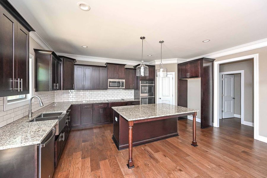 Kitchen with dark brown cabinets, granite countertops, and hardwood floors.