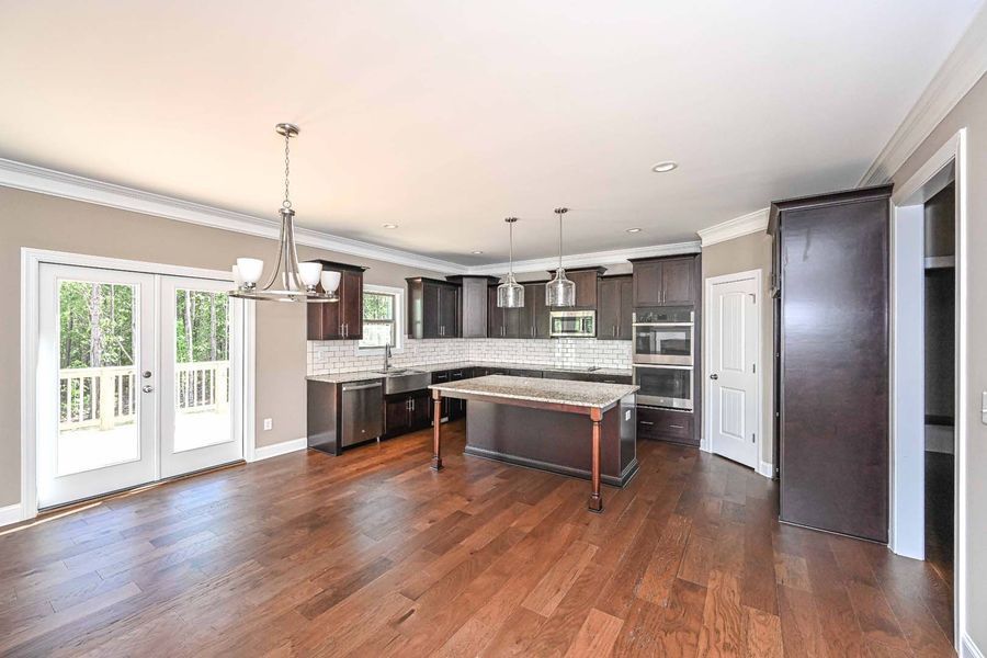 Open kitchen with dark cabinets, a wooden island, and hardwood floors. French doors lead to a deck.