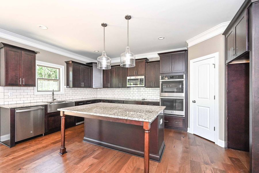 Kitchen with dark wood cabinets, island, and hardwood floors. Stainless steel appliances.