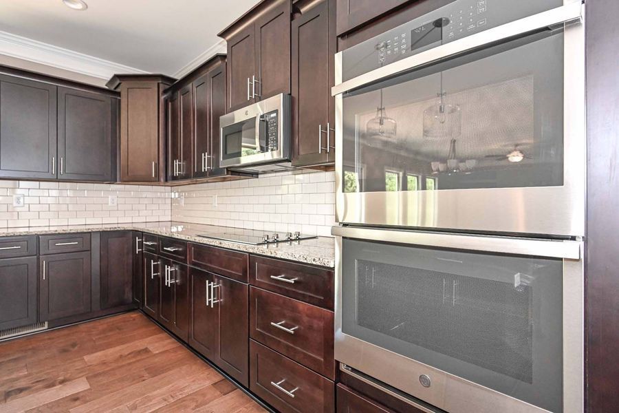 Dark wood kitchen with stainless steel appliances, including a double oven and microwave