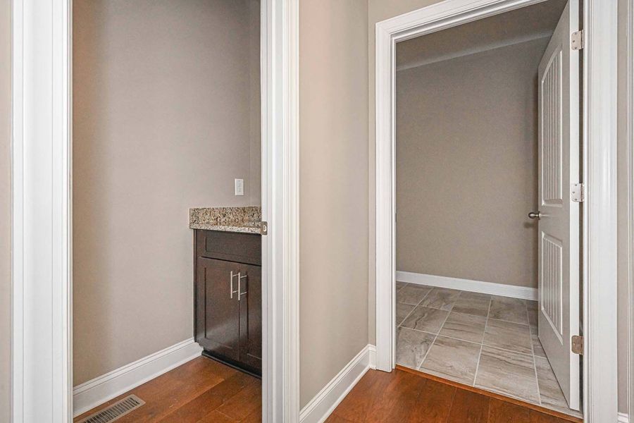 Hallway with a dark wood cabinet and a doorway leading to a tiled room.