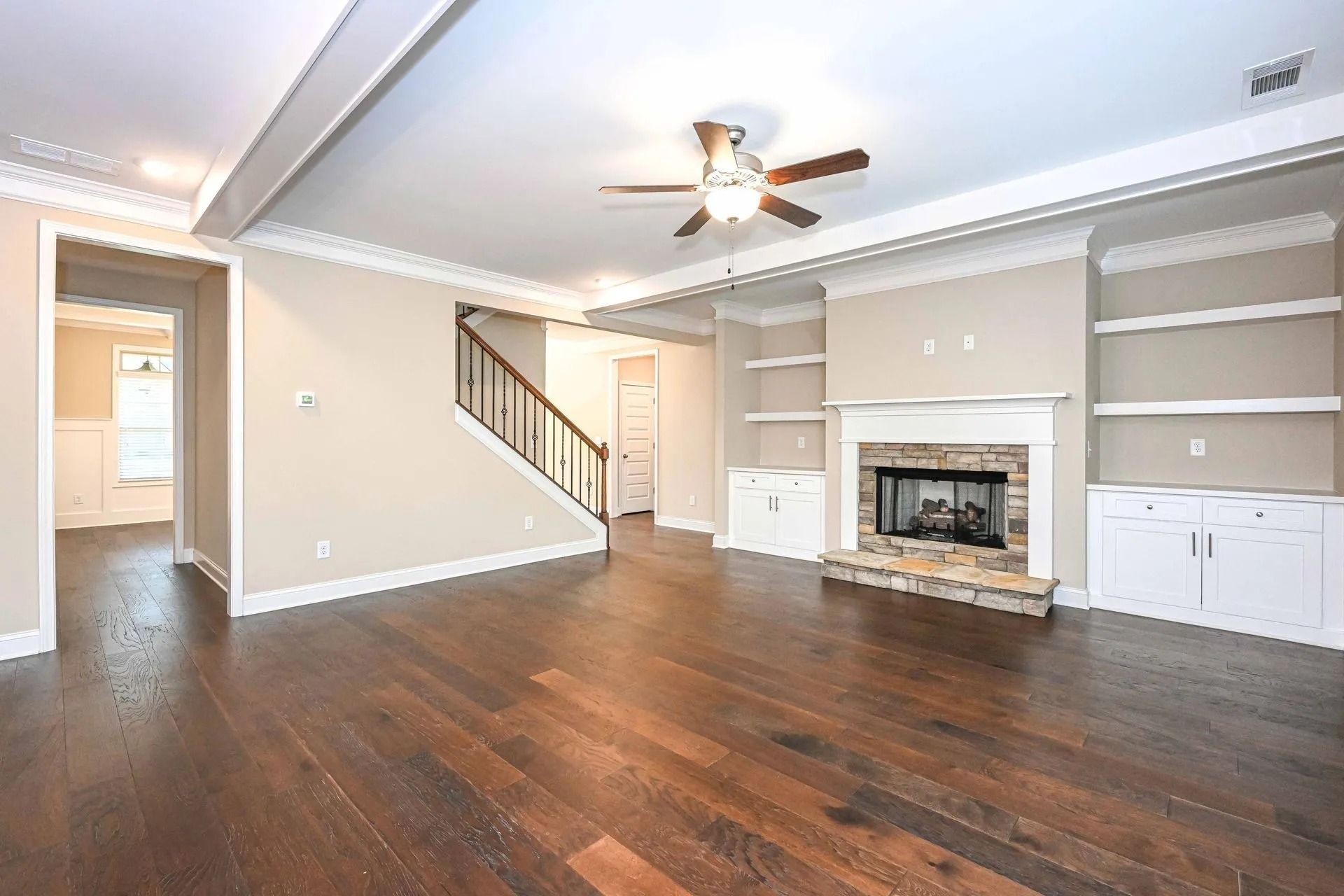 Living room with fireplace, built-in shelves, dark wood floors, and neutral walls.