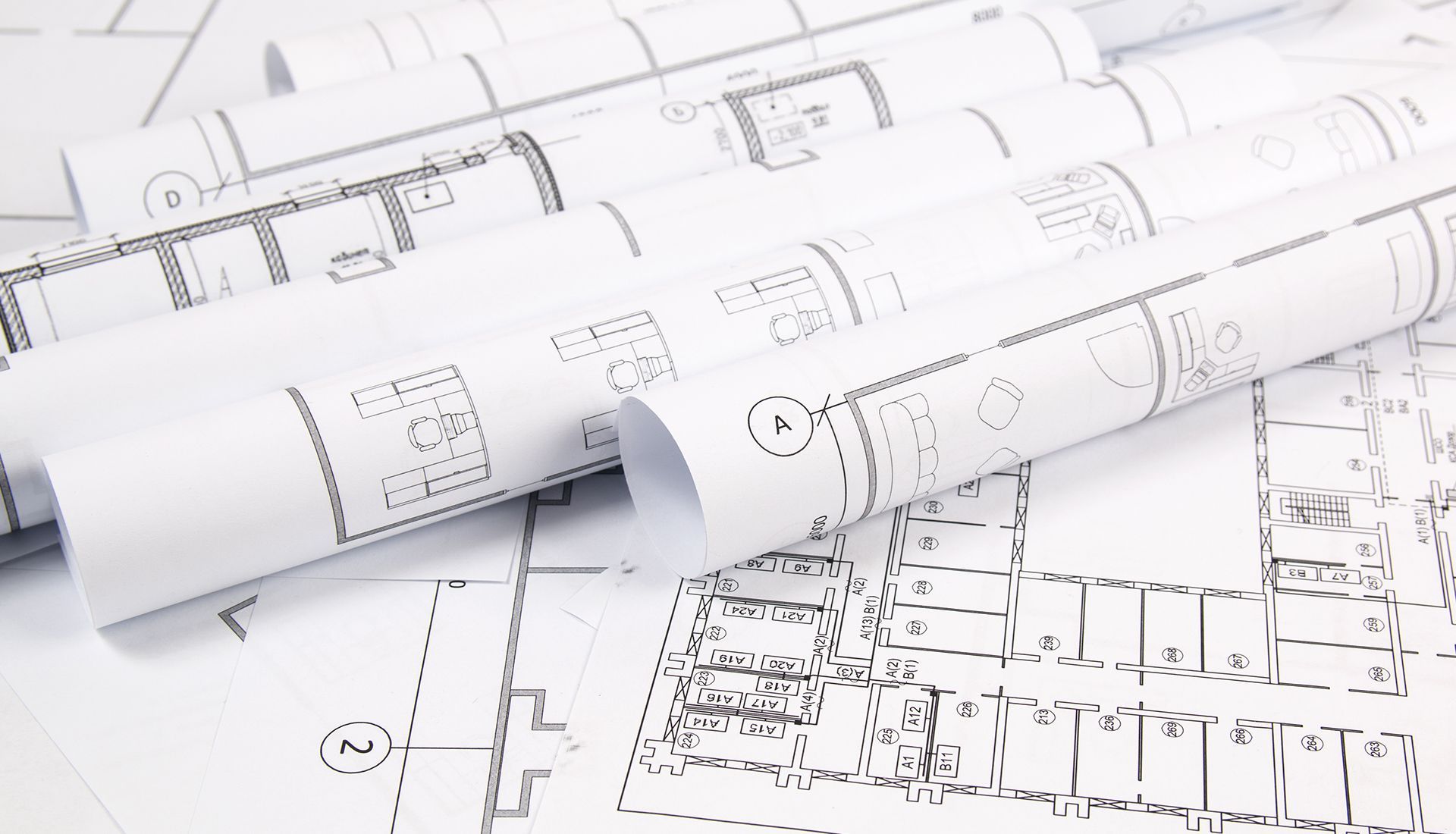 Blueprints, rolled and stacked, with detailed architectural plans.