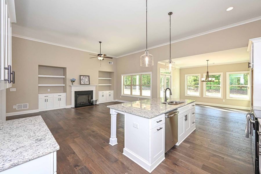 Open-concept kitchen and living area with white cabinets, granite countertops, and hardwood floors.