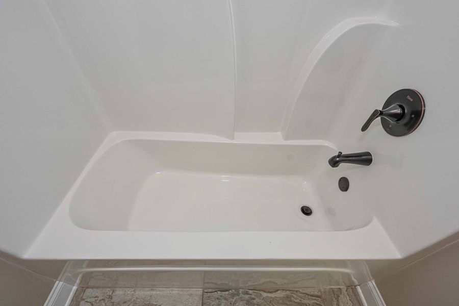 White bathtub with black faucet in a white-walled bathroom.