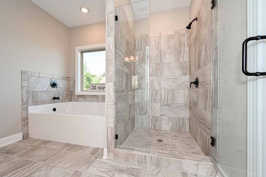 Bathroom with tiled floor, walk-in shower, tub, and window. Light grey tones.
