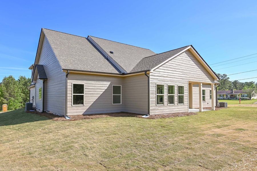Beige house with dark roof on a grassy lot, blue sky in the background.