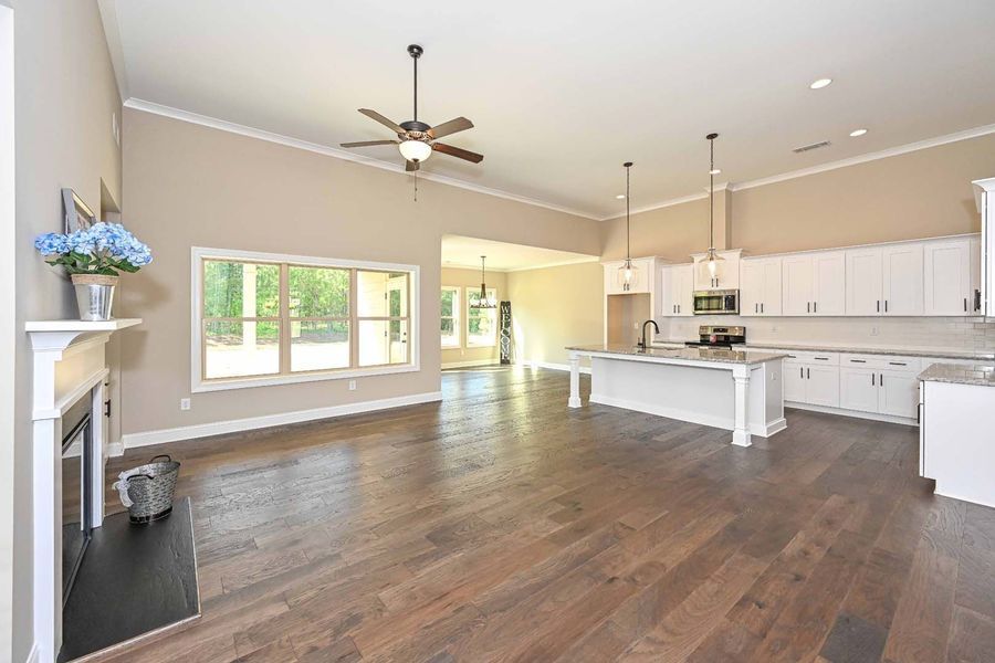 Spacious open-concept kitchen and living area with hardwood floors, white cabinets, and a kitchen island.