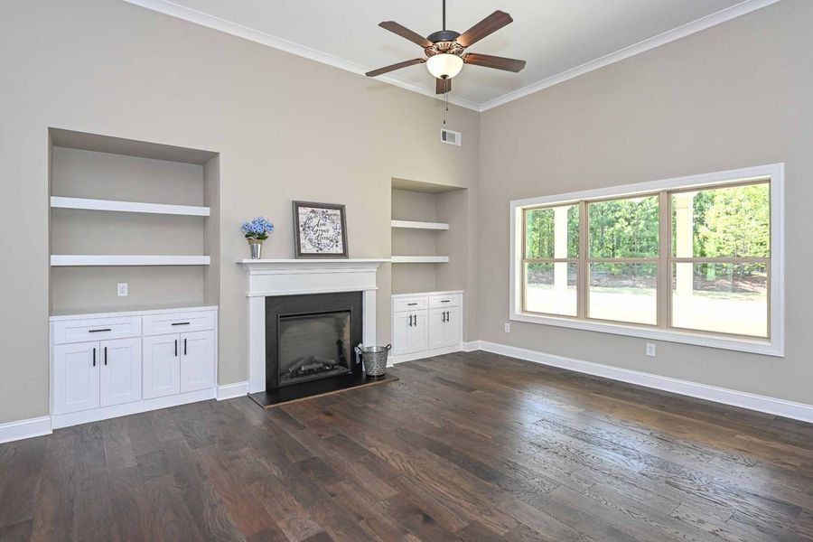 Living room with fireplace, built-in shelves, and dark hardwood floors. Large window lets in natural light.