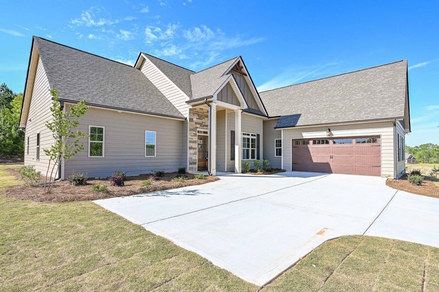 Tan, one-story house with brown garage door and driveway, on a sunny day.