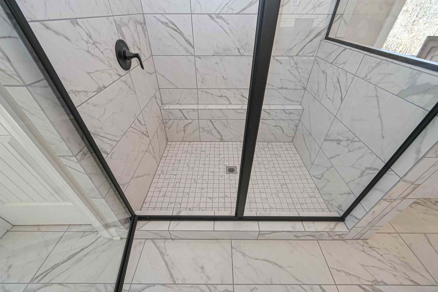 Shower with white marble tiles, black trim, and a black showerhead.