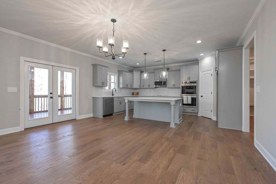 Spacious kitchen with gray cabinets, island, and wood floors. French doors lead to a balcony.