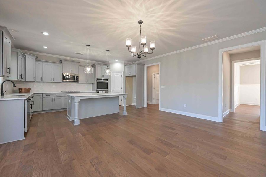 Light gray kitchen with island, hardwood floors, and open doorway.