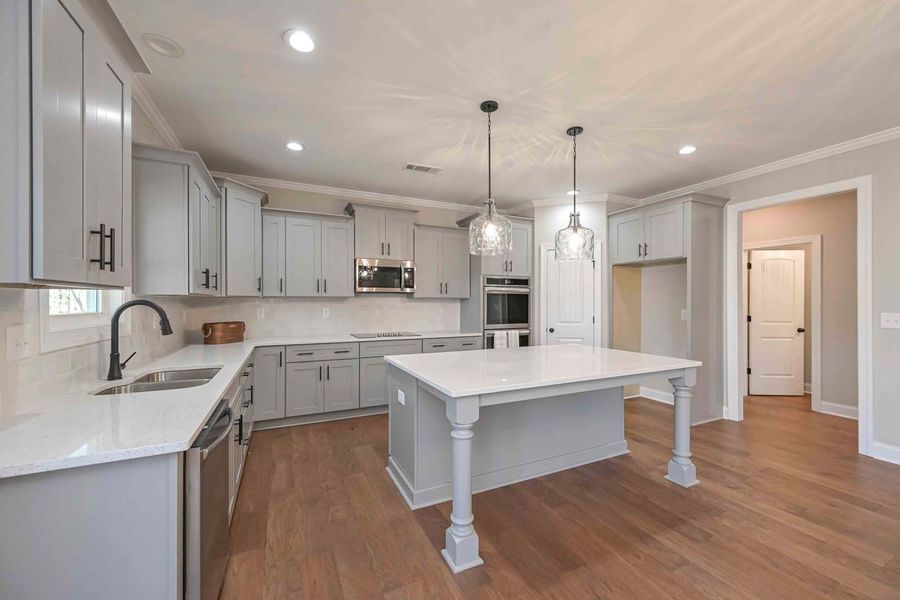 Modern gray kitchen with white countertops, stainless steel appliances, and wooden floors.