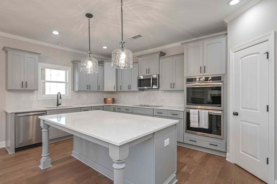 Gray kitchen with island, cabinets, stainless steel appliances, and pendant lights.