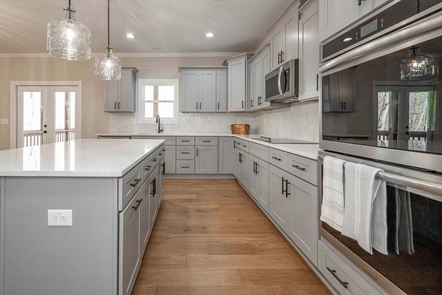 Gray kitchen with light wood floors, white countertops, and stainless steel appliances.