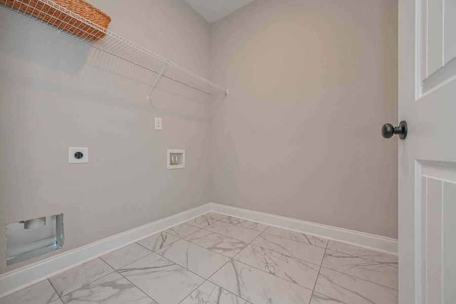 Empty laundry room with marble tile floor, gray walls, and a white door.