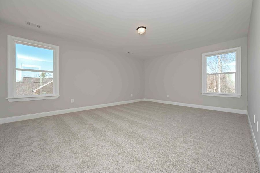 Empty bedroom with gray walls, carpet, and two windows.