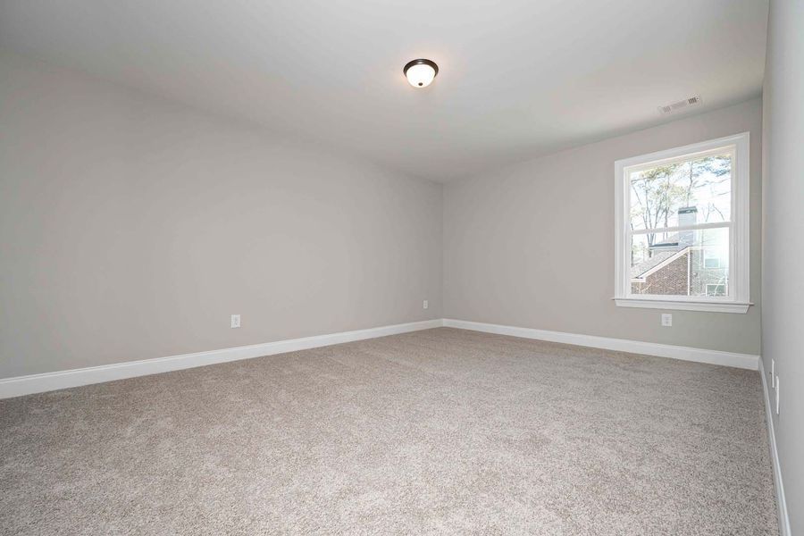 Empty room with gray walls, tan carpet, a window, and a ceiling light.