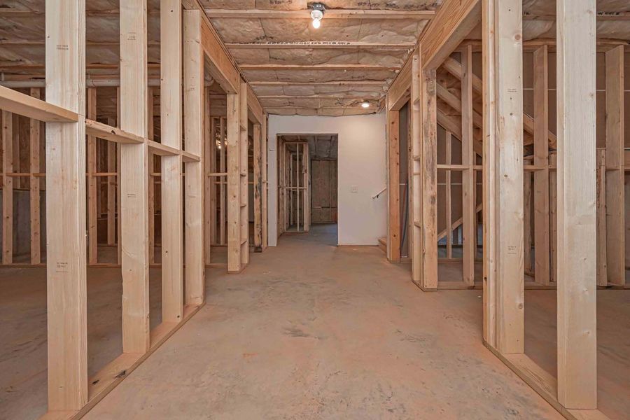 Interior of unfinished construction with wooden frames forming walls and a hallway.