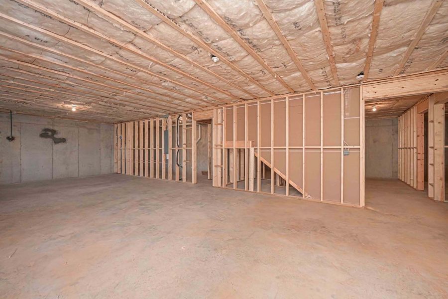 Unfinished basement with exposed wood framing, insulation, concrete floor, and partially constructed walls.