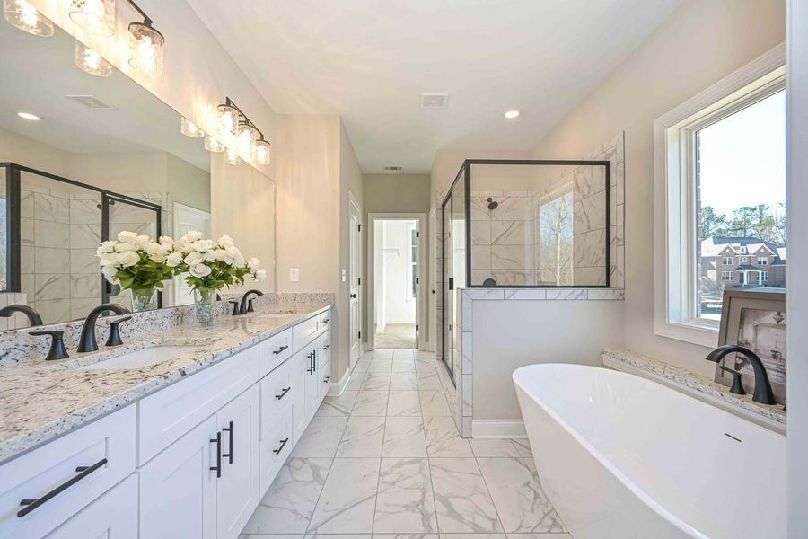 White modern bathroom with double sinks, bathtub, and glass shower.