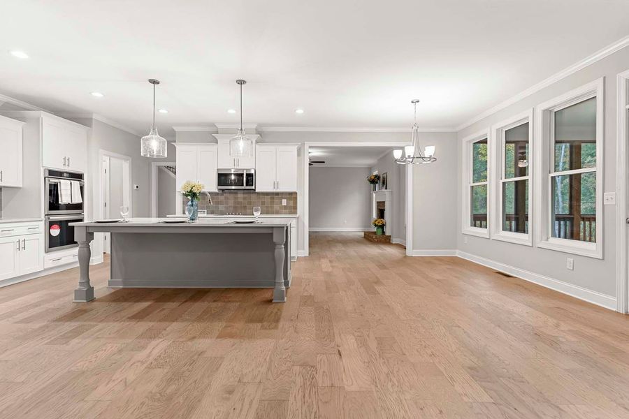 Spacious modern kitchen with grey island, white cabinets, and light wood floors.