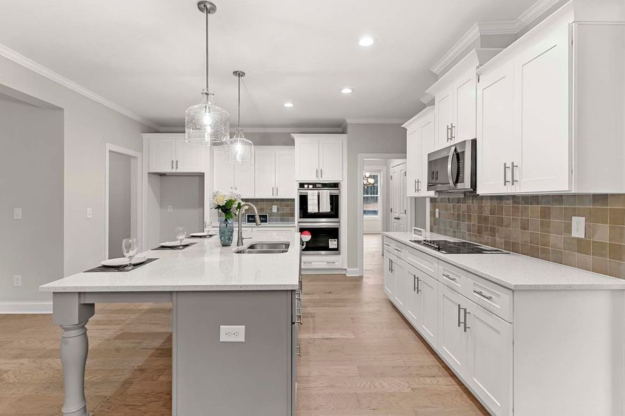 Modern white kitchen with island, cabinets, light wood floors, and stainless steel appliances.