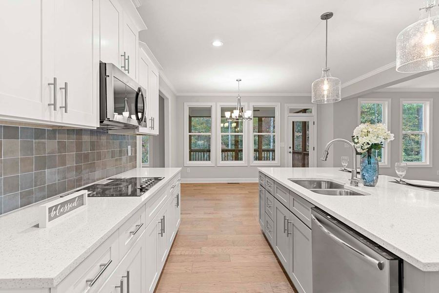 Modern kitchen with white cabinets, gray backsplash, and island with sink.