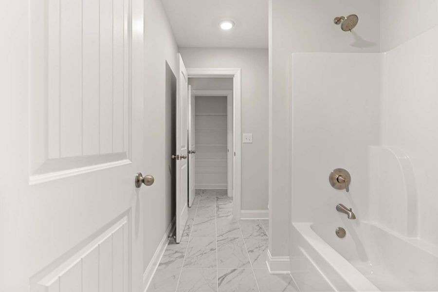 Bathroom hallway with a bathtub, door, and closet, all in white and gray.