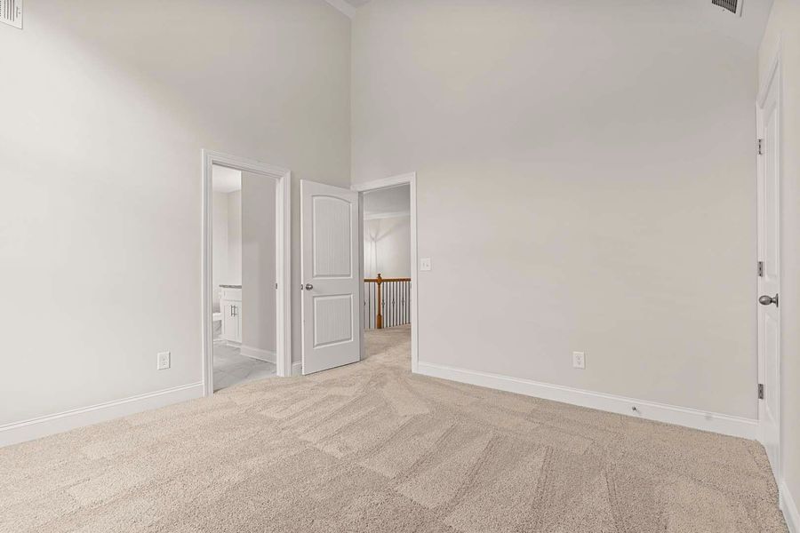 Empty bedroom with carpet, white walls, and three doorways.