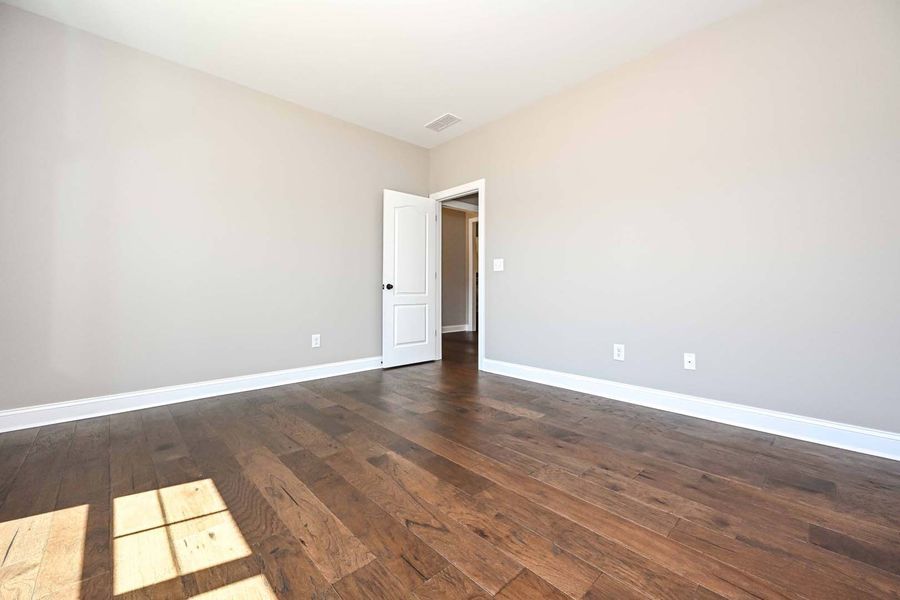 Empty room with wood floor, neutral walls, and open door.