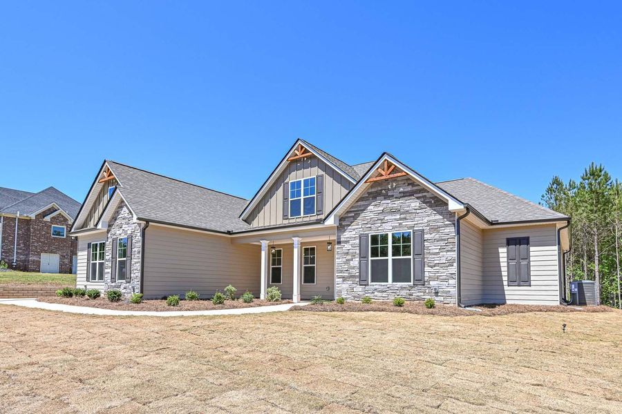 Beige and stone ranch house with blue sky and dry grass.