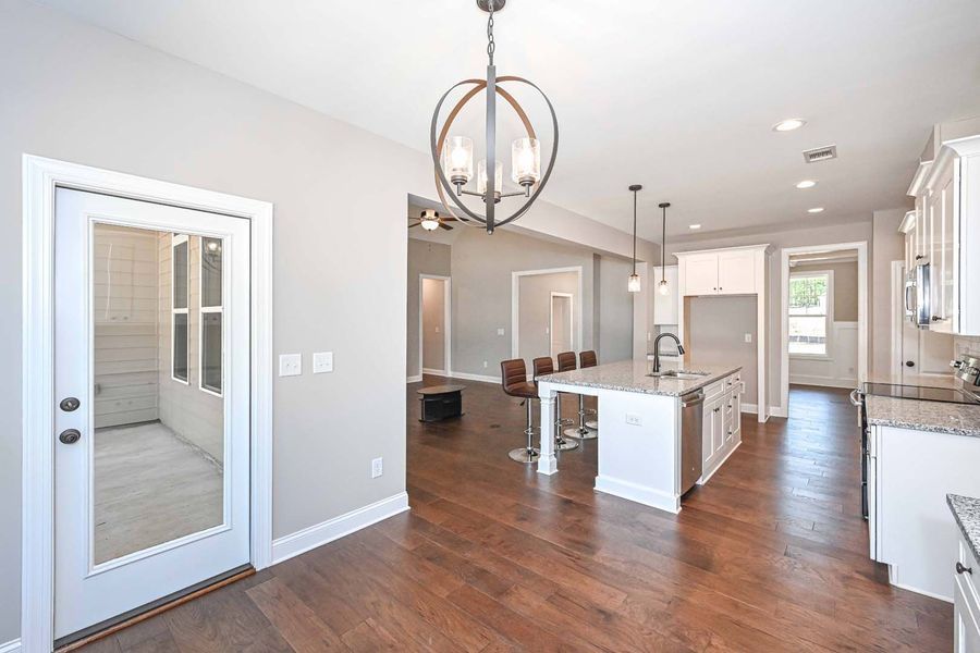 Open kitchen with island, dark wood floors, and a door to the porch.
