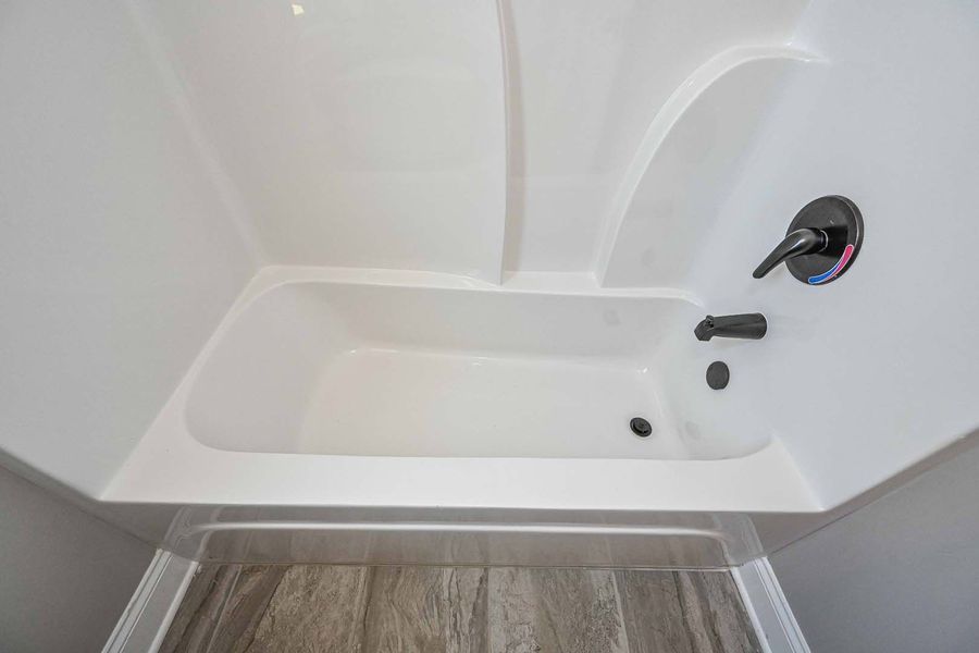 White bathtub with black fixtures in a bathroom.
