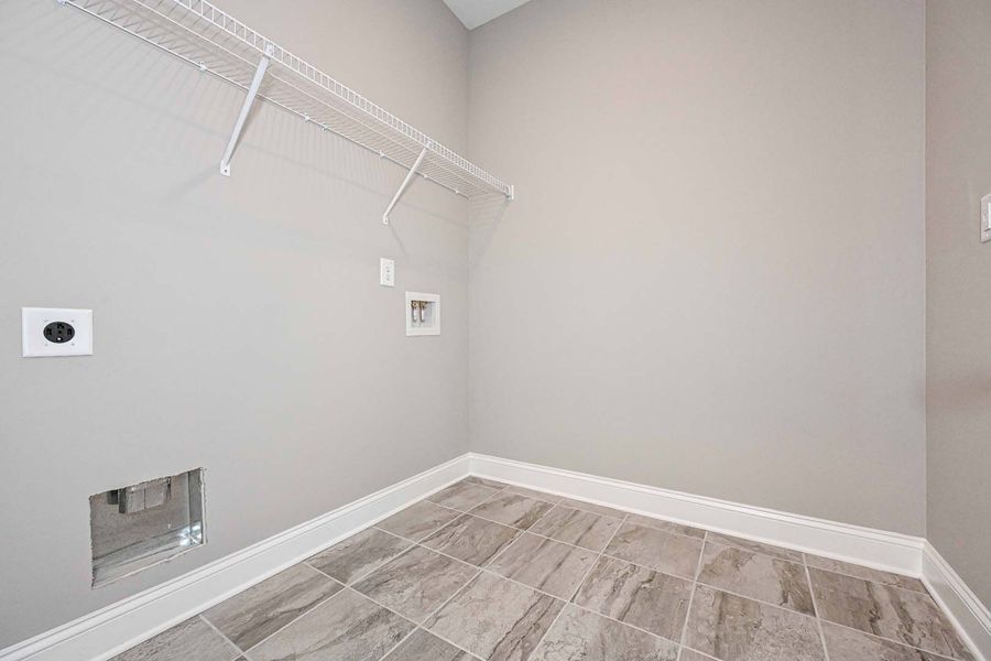 Empty laundry room with light gray walls, tile floor, and wire shelving.