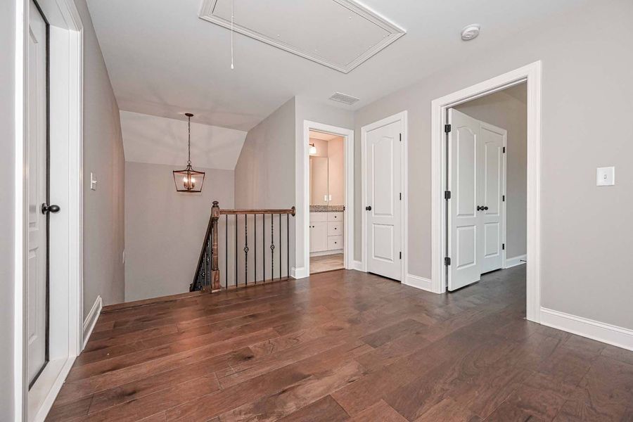 Hallway with wood floors, stairs, and doors to rooms.