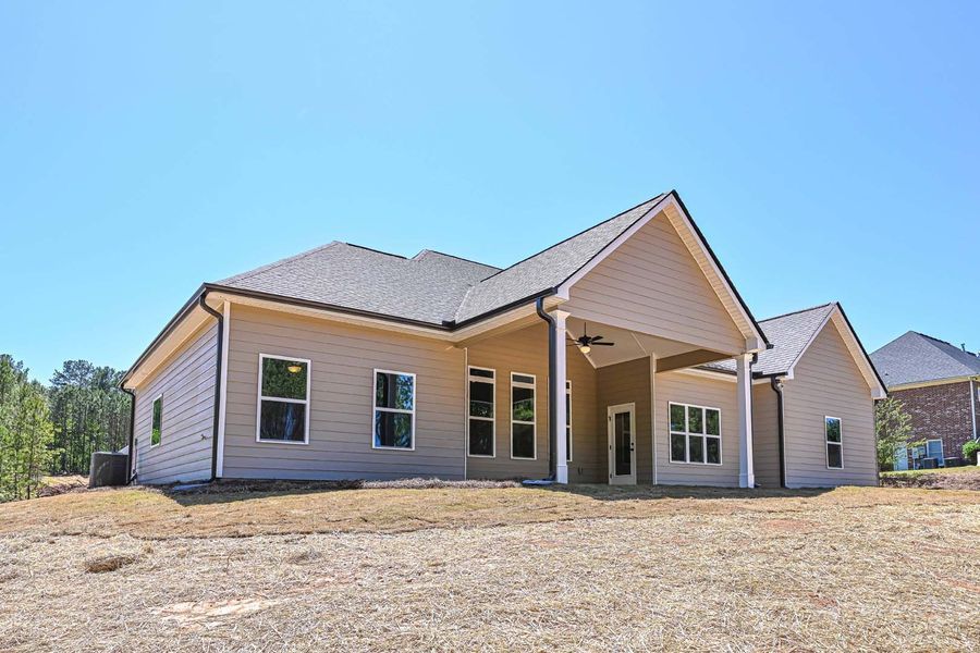 Beige house exterior with multiple windows and a covered patio, under a bright blue sky.