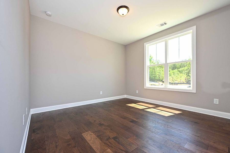 Empty room with dark wood floors, gray walls, a window, and a ceiling light.