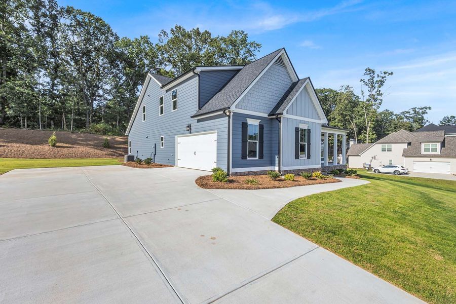 Blue house with white garage door, surrounded by concrete driveway and green lawn.