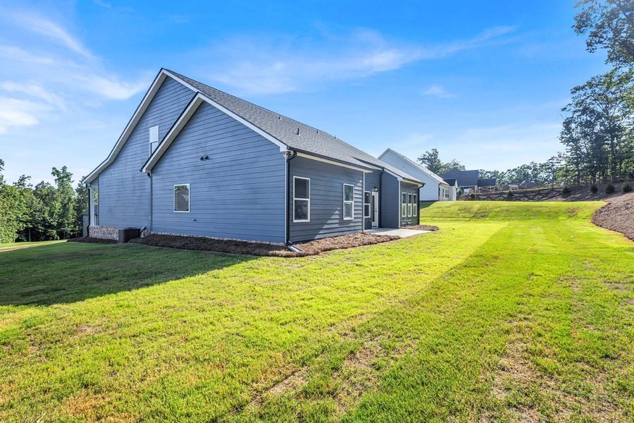 Blue house with green lawn, trees and blue sky.