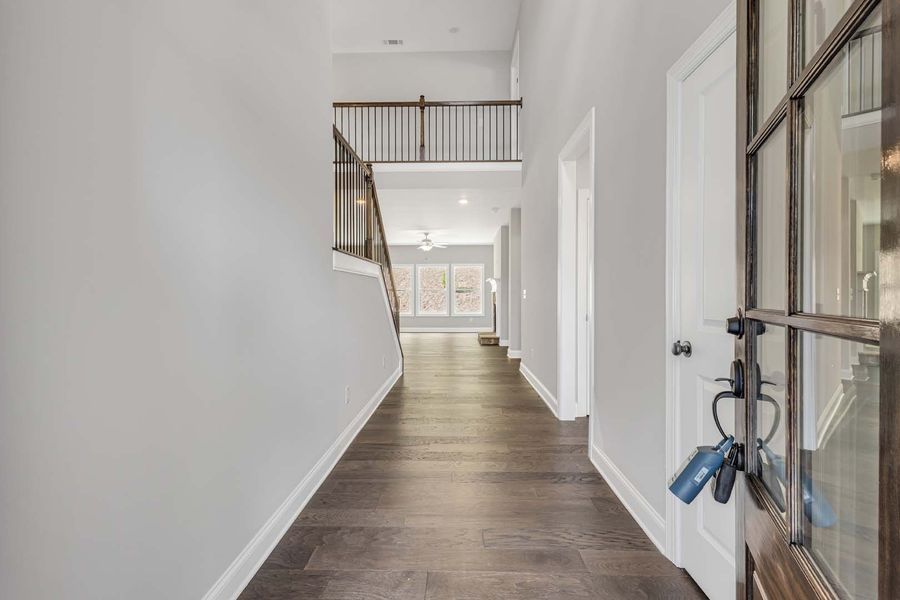 Hallway with hardwood floor, gray walls, staircase, and open door with keys.